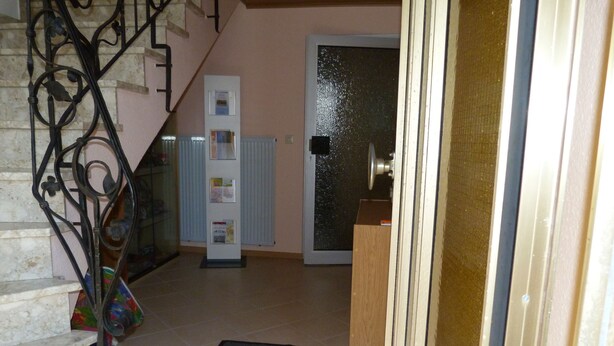 A staircase with a metal railing leading to a landing. There is a door with a glass panel and a wooden door frame. A bulletin board with papers is visible on the wall. - Apartment "Eifel Nest" between VULKANEIFEL and Moselle (Urschmitt)