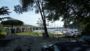 A beachside area with a gazebo, a sandy walkway, and a marina with boats.
