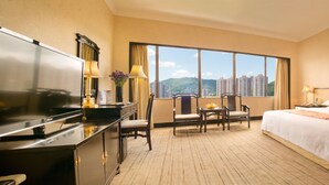 A hotel room with a bed, desk, chairs, and a large window offering a city view. - Yindo Jasper Hotel Zhuhai (Zhuhai)