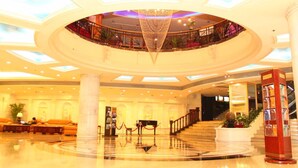 A spacious lobby with a central staircase, a chandelier, and a reception desk. - Yindo Jasper Hotel Zhuhai (Zhuhai)