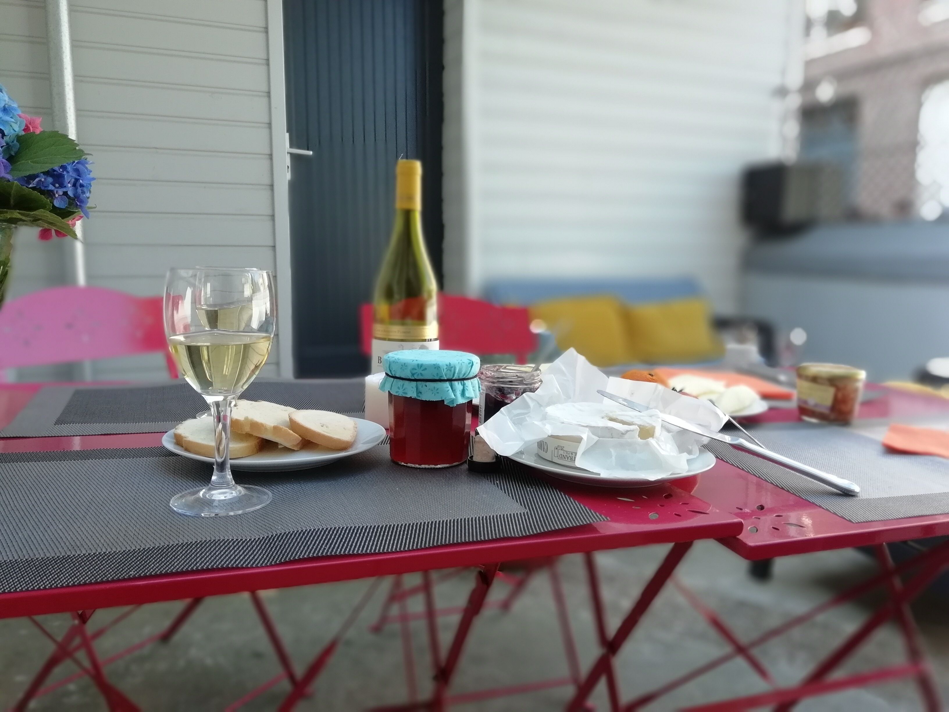 Un tavolo con una bottiglia di vino bianco, un bicchiere di vino bianco e piatti con cibo e formaggio.
