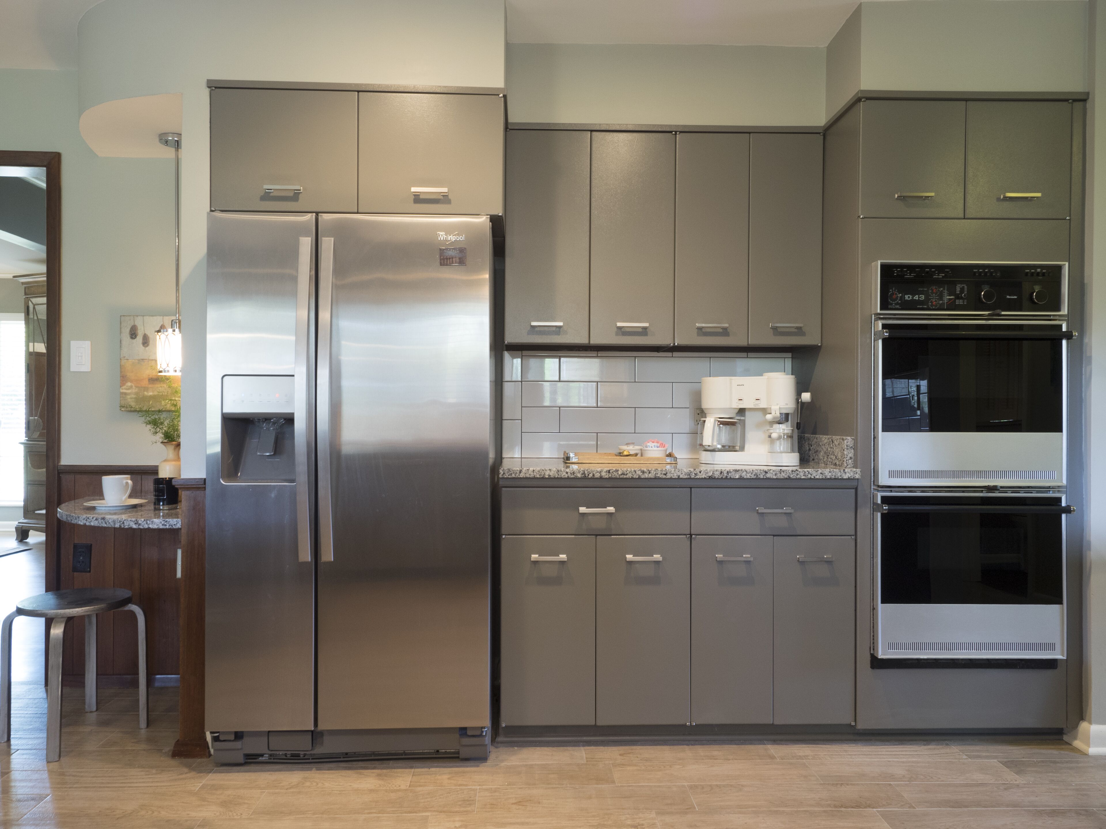 A modern kitchen with stainless steel appliances, grey cabinets, and a granite countertop.