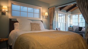 A bedroom with a large bed, two wall-mounted lamps, and a window with curtains.