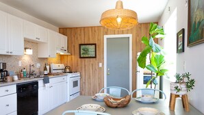 Una cocina moderna con armarios blancos, encimera de madera y un comedor con una mesa preparada para cuatro.