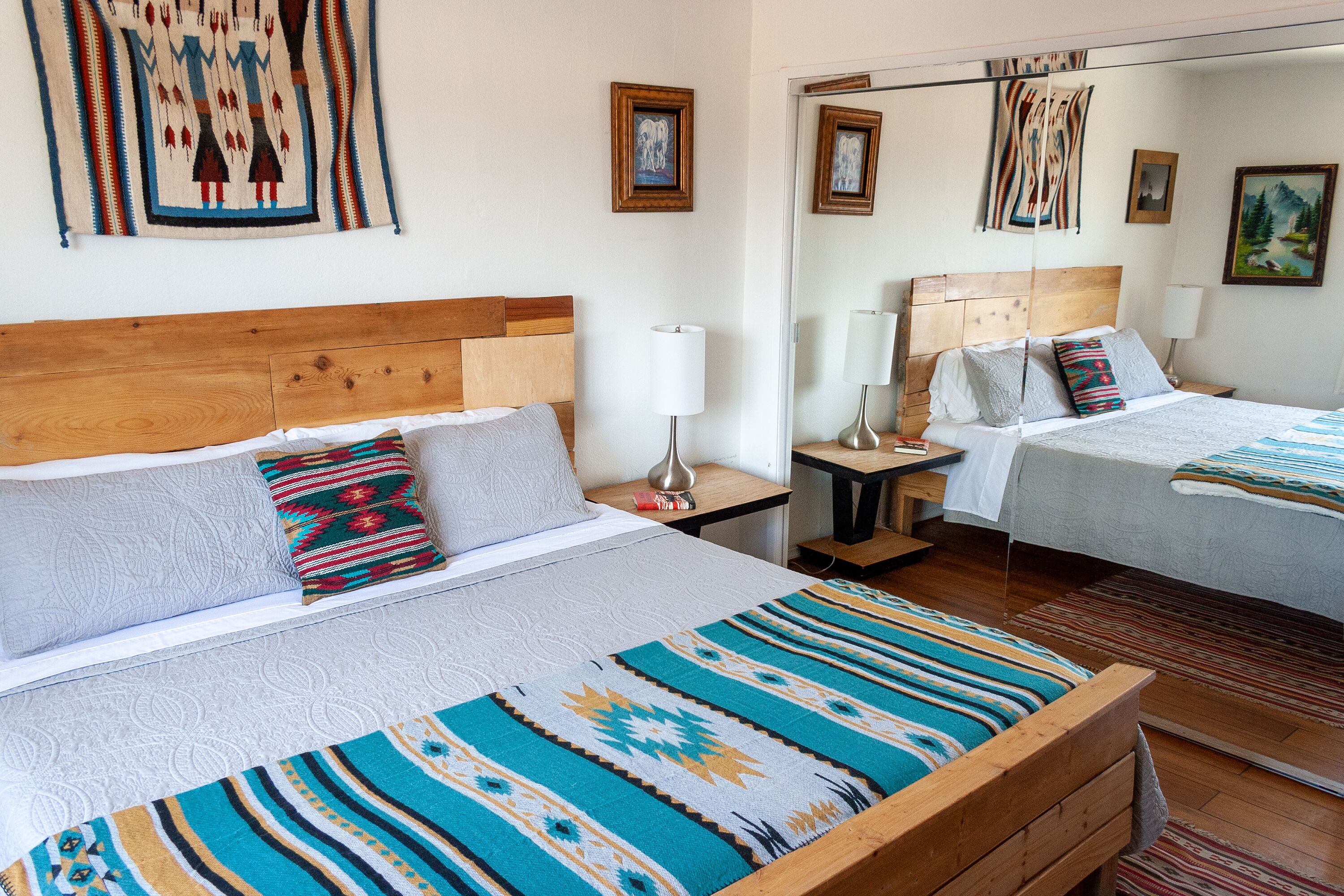 A hotel room with two beds, wooden headboards, and a large mirror.