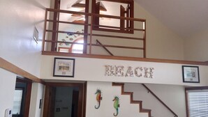 A multi-level living space with a staircase, a framed picture, and a decorative word 'BEACH' on the wall. - Family Sized Home - 2 Blocks from the Beach and Bay!!!! (Galveston)