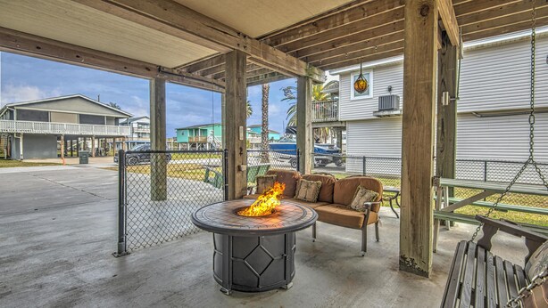 A covered outdoor area with a fire pit, seating, and a view of nearby buildings.