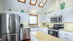 A modern kitchen with stainless steel appliances, white cabinets, and a wooden countertop.