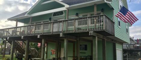 A two-story building with a balcony, a flag, and outdoor seating.