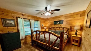 A wooden cabin bedroom with a bed, dresser, and ceiling fan. - Creekside Log Cabin, Ideal Family Vacation! Hot tub, Fire Pit, Tubing, Fishing (Robbinsville)