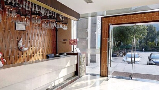 A reception area with a wooden wall, a reception desk, and a glass door leading outside. - S&N Niutoushan Resort (Taizhou)