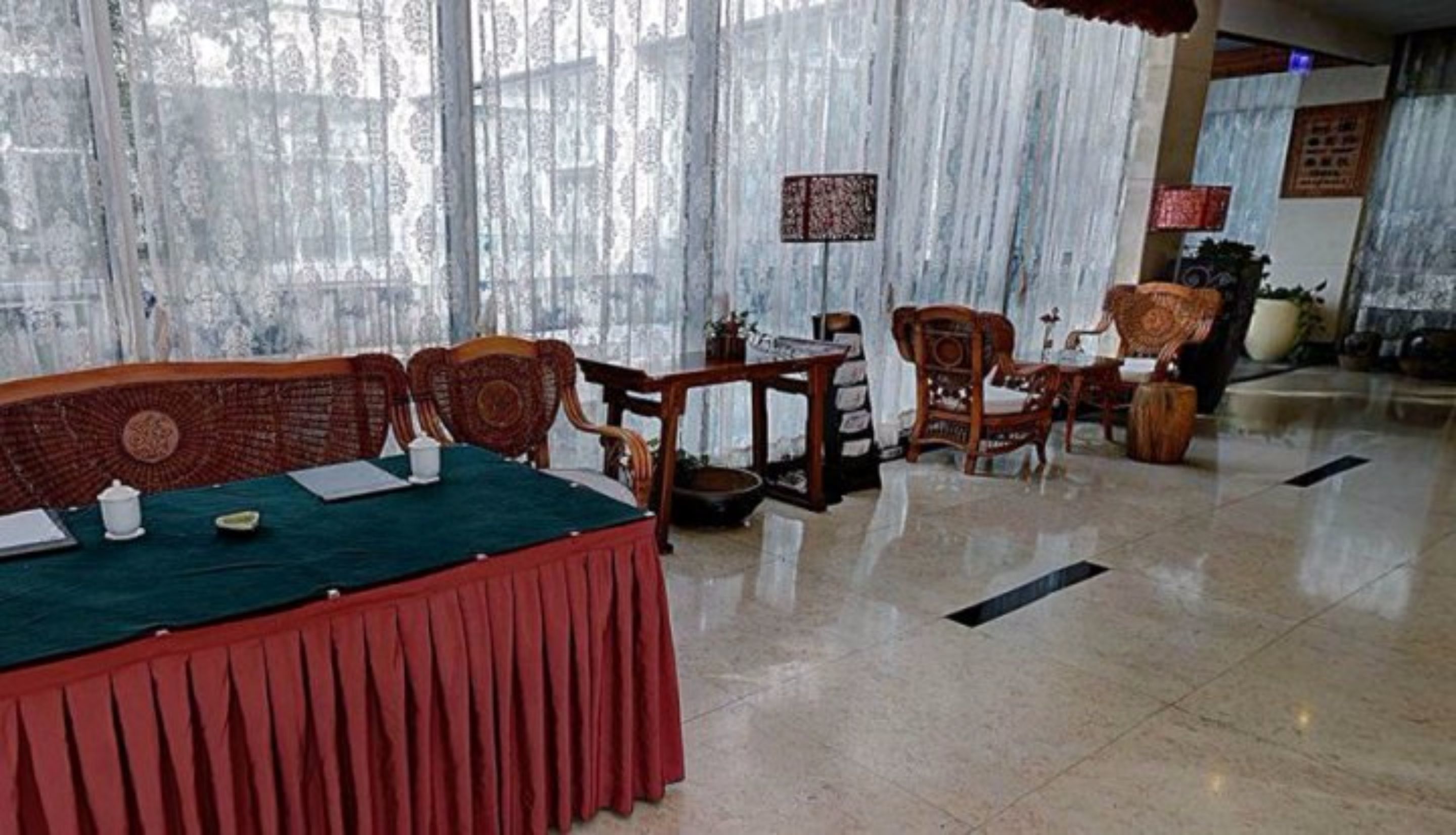 Un salón de conferencias con una larga mesa, sillas y un panel decorativo.