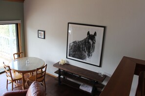 Ein Essbereich mit einem runden Tisch, Holzstühlen, einer Bank und einem Bilderrahmen mit einem Pferdegemälde an der Wand.