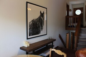 Ein gerahmtes Schwarz-Weiß-Pferd-Gemälde an einer Wand, eine hölzerne Bank mit Kerzen und eine Treppe.
