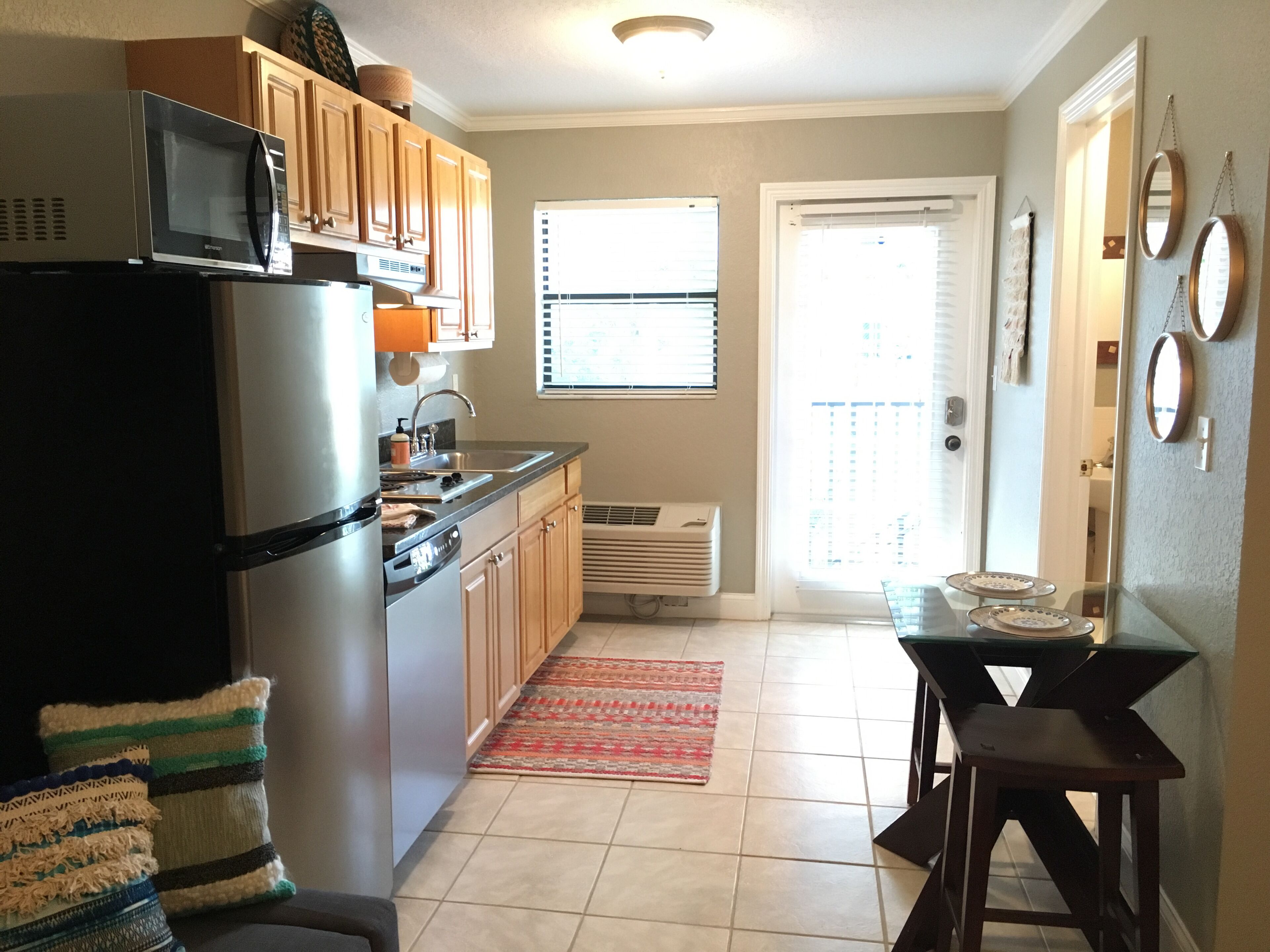 Cocina compacta con refrigerador, microondas, pileta y una pequeña mesa de comedor.