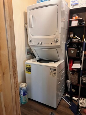 A compact, white front-loading washer and dryer unit with an ENERGY GUIDE sticker, placed in a small laundry room with wooden flooring.