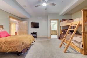 A bedroom with bunk beds, a television, and a ceiling fan.
