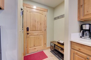 A wooden door with a keyhole and a handle, a small table with a red mat, a coffee maker, and a shelf with a basket. - BEST Location Park City: Walk In Out Ski. Town, Trails, Garage (PARK CITY)