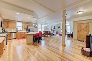 A spacious kitchen with wooden cabinets, a stainless steel refrigerator, and a large island with bar stools.