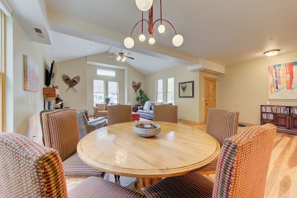 A spacious living area with a round wooden table, comfortable seating, and a ceiling fan.