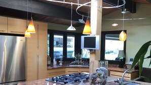 A modern kitchen with a central island, stainless steel appliances, pendant lighting, and a large window. - Exceptional retreat near University of Oregon Athletics. Casa del Roots (Eugene)