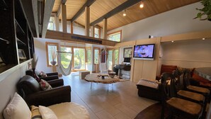 A spacious living area with a sofa, chairs, a coffee table, and a TV mounted on the wall. - Exceptional retreat near University of Oregon Athletics. Casa del Roots (Eugene)