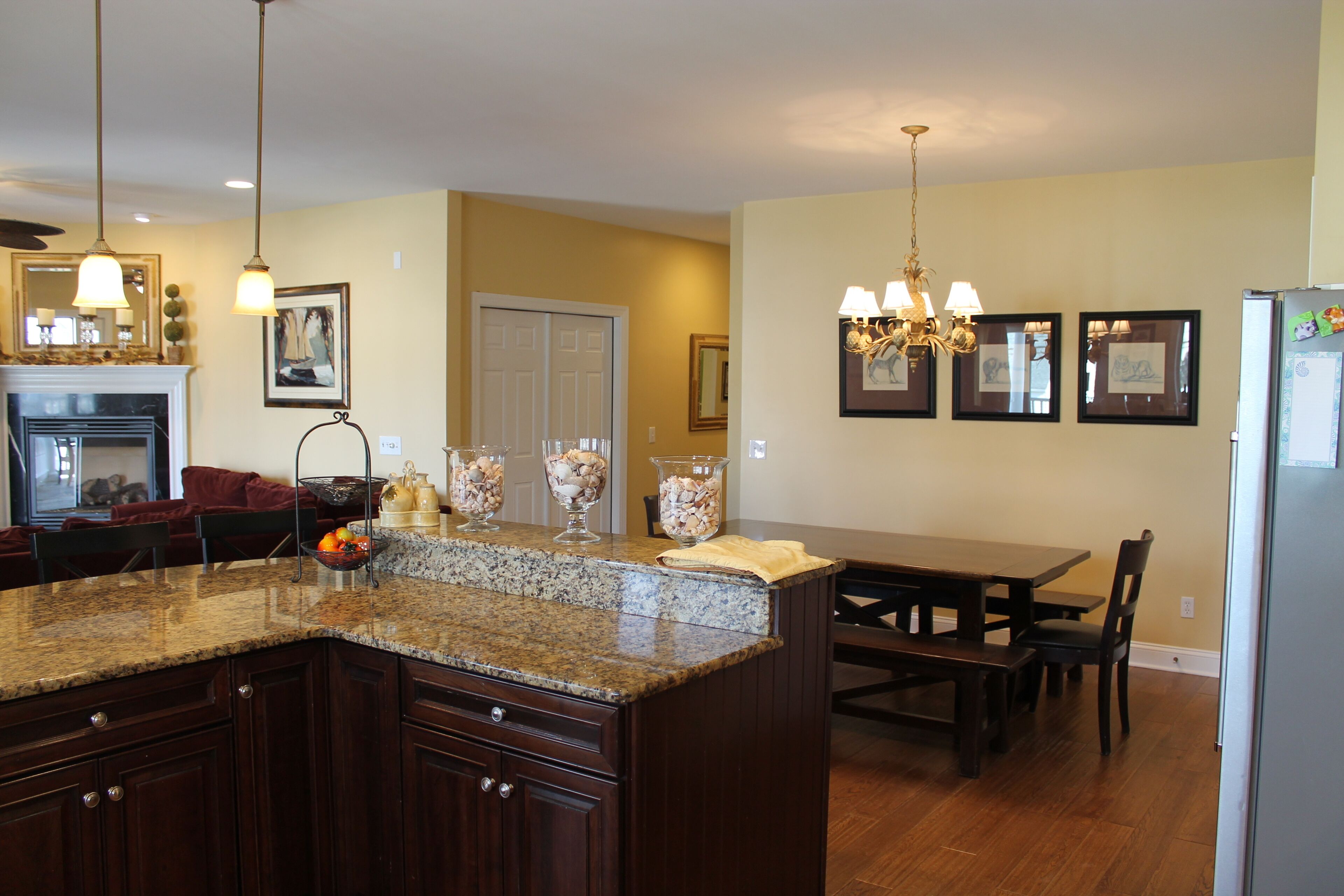 A kitchen with granite countertops, wooden cabinets, a dining table, and a chandelier.