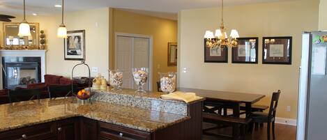 A kitchen with granite countertops, wooden cabinets, a dining table, and a chandelier.