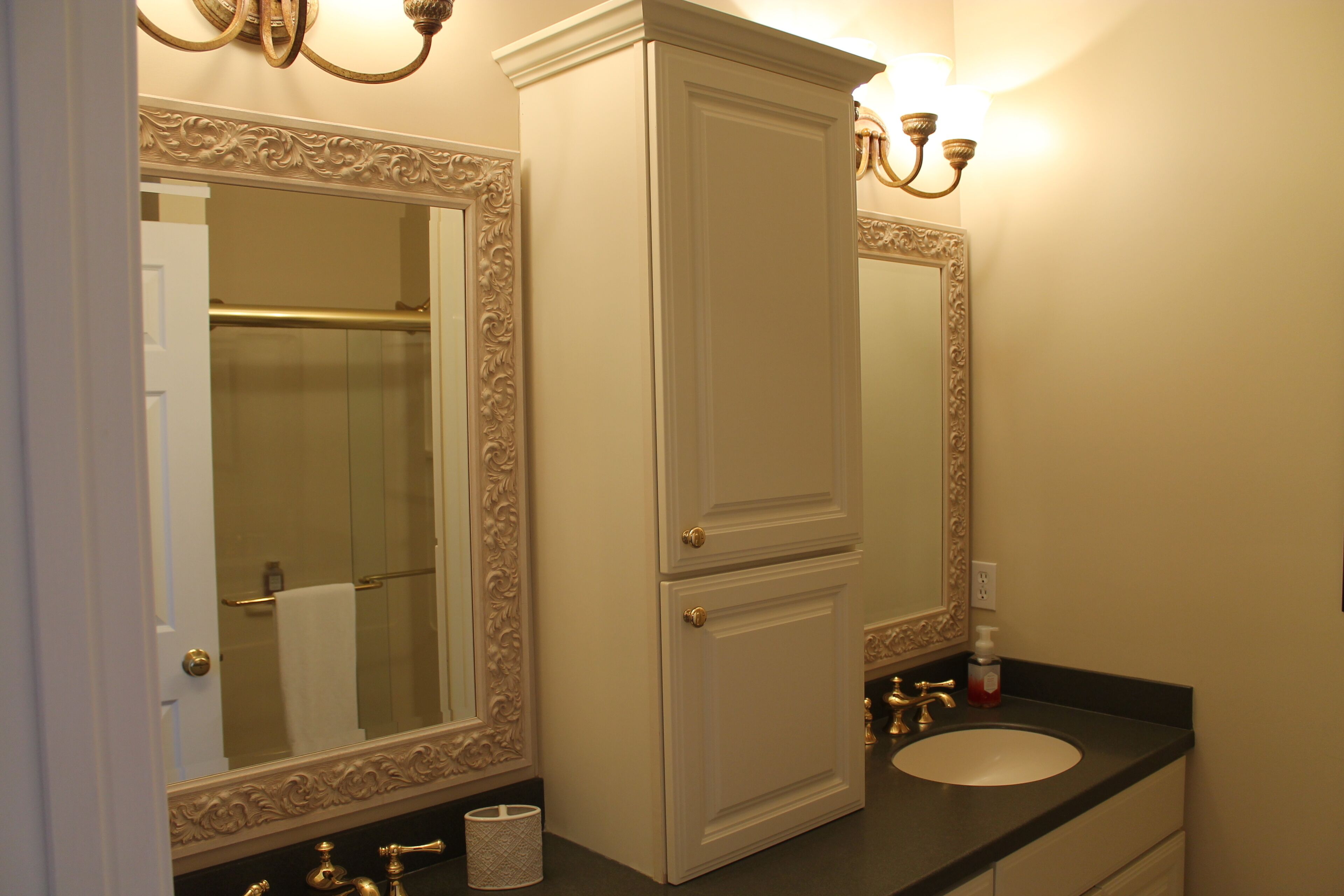 Un baño con lavamanos doble, un espejo con marco decorativo y un perchero para toallas.