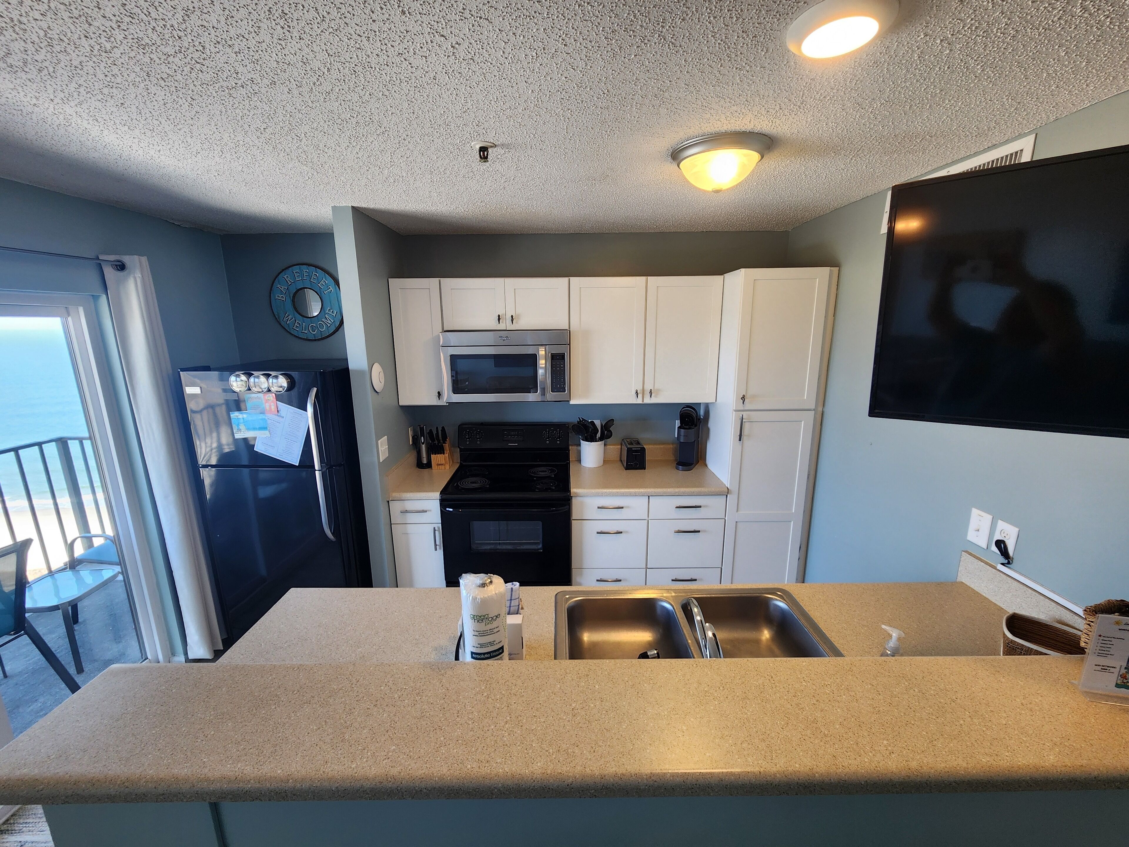 A kitchen with a refrigerator, microwave, stove, and sink.