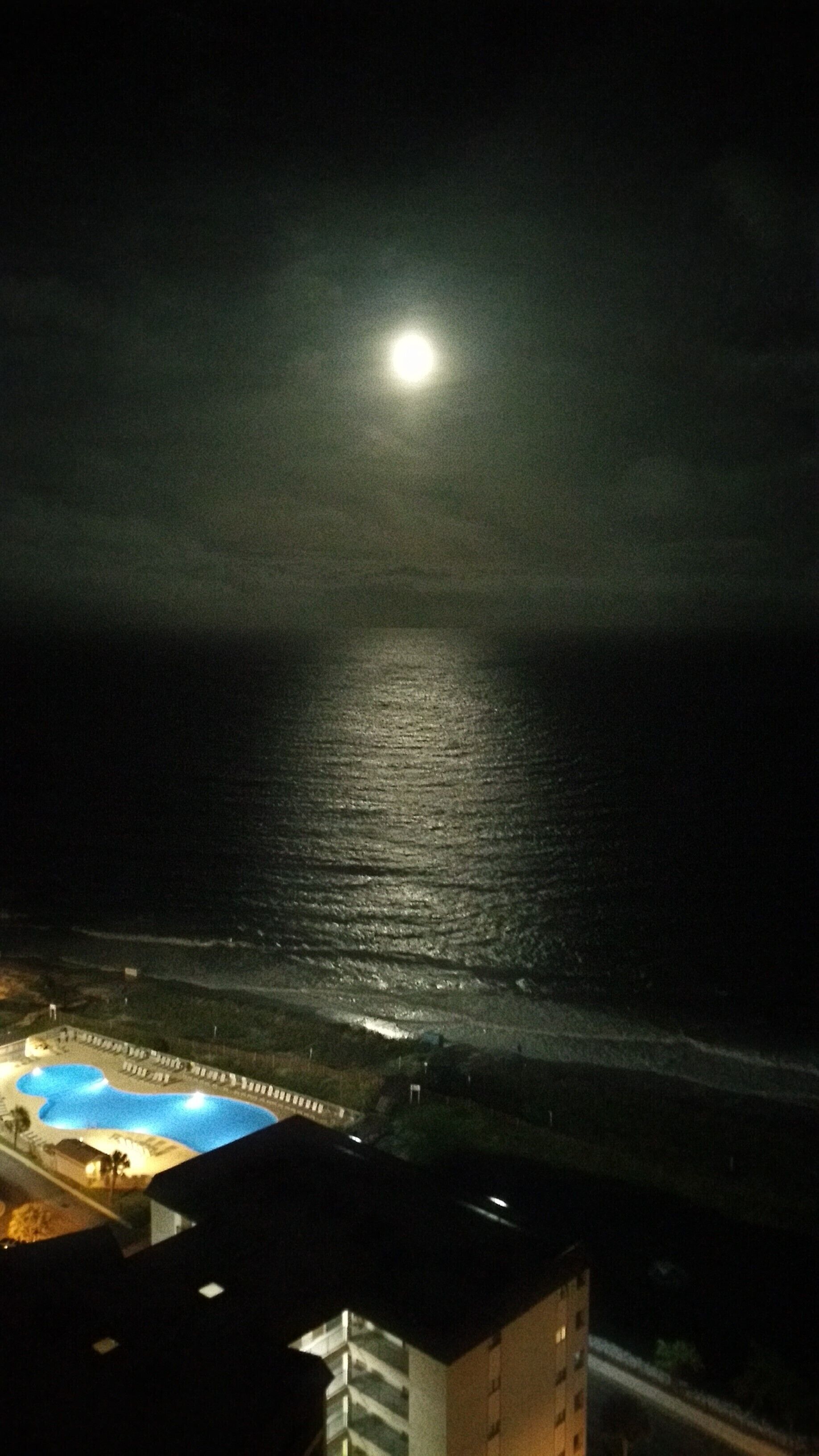 Ein Nachtblick auf einen Strand mit Pool und einem Gebäude im Vordergrund.