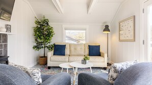 A cozy living room with a white sofa, two grey armchairs, a small white coffee table, a potted plant, and a floor lamp.