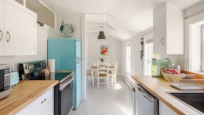 A modern kitchen with white cabinetry, a teal refrigerator, and a wooden countertop.