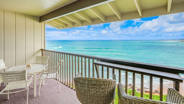 A balcony with a view of the ocean, wicker chairs, and a table. - "Picture Perfect" Oceanfront on the Top Floor at Wailua Bay View! (Kapaa)