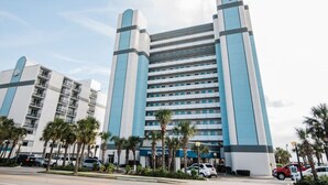 A multi-story hotel with a modern design, featuring a prominent vertical structure and a series of balconies. - Direct Oceanfront, In the middle of happening area (Myrtle Beach)