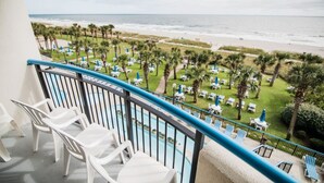 A balcony with a view of a beach and a pool area with sun loungers and umbrellas. - Direct Oceanfront, In the middle of happening area (Myrtle Beach)