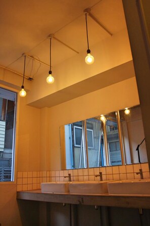 A bathroom with two sinks, a large mirror, and pendant lighting.