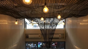 A modern interior with a unique ceiling design, visible air conditioning units, and a view of the street outside. - Pho Hostel (Bangkok)