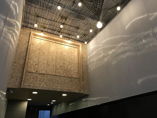 A modern interior with a high ceiling, exposed wooden paneling, and recessed lighting.