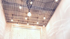 A group of people seated at a table in a restaurant with a high ceiling and pendant lighting. - Pho Hostel (Bangkok)