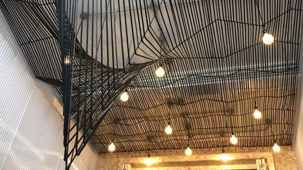 A ceiling with a grid of metal beams and hanging light bulbs. - Pho Hostel (Bangkok)