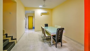 A conference room with a glass table, four chairs, and a yellow door in the background. - The Home Homestay (Kuala Lumpur)