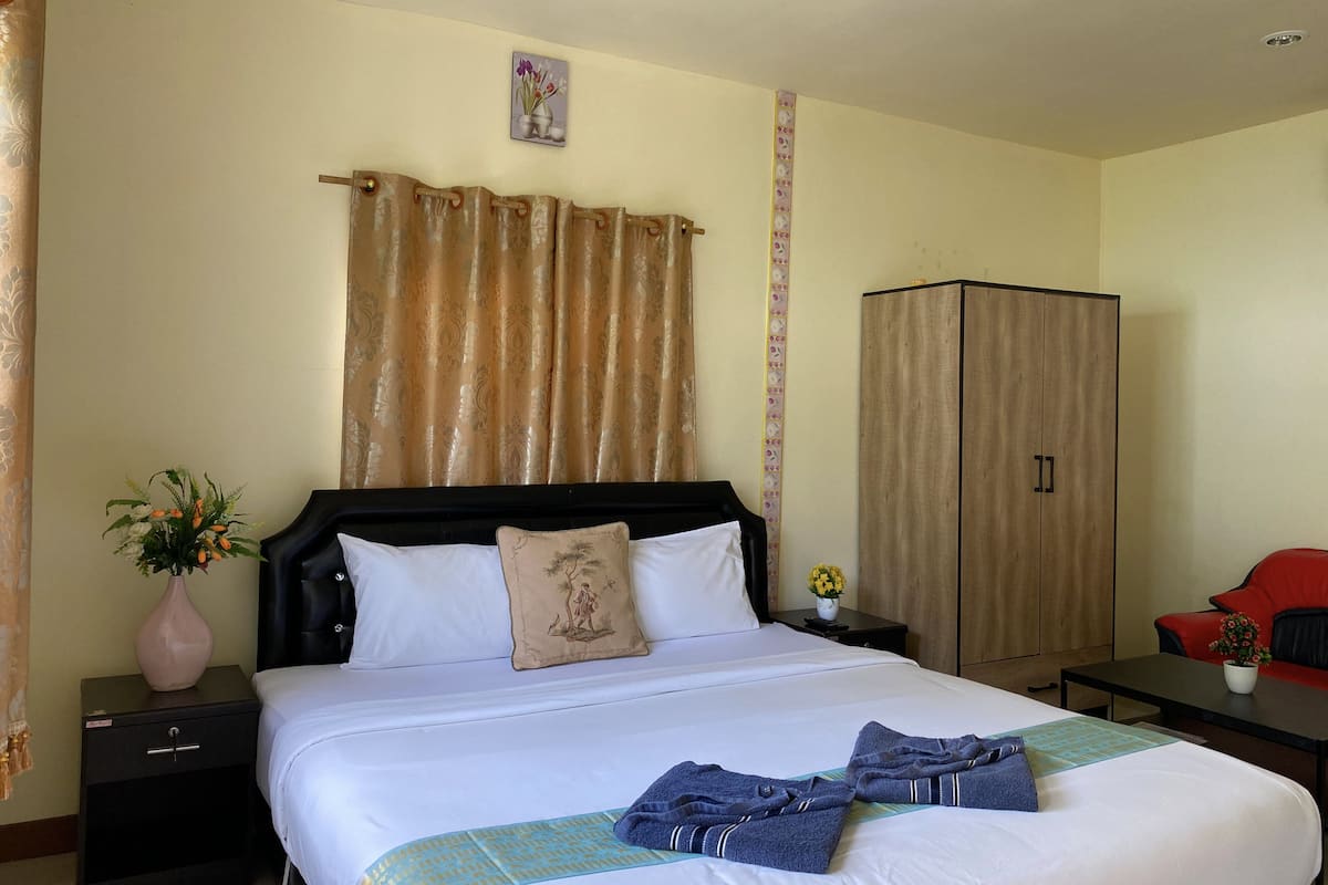 A hotel room with a bed, a nightstand, a wardrobe, and a red sofa.