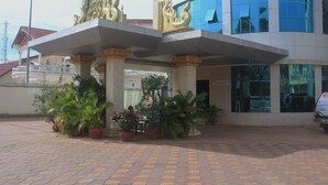 A building with a modern architectural design, featuring a large entrance with ornate golden decorations and potted plants. - 7 Makara Hotel (Kampong Cham)