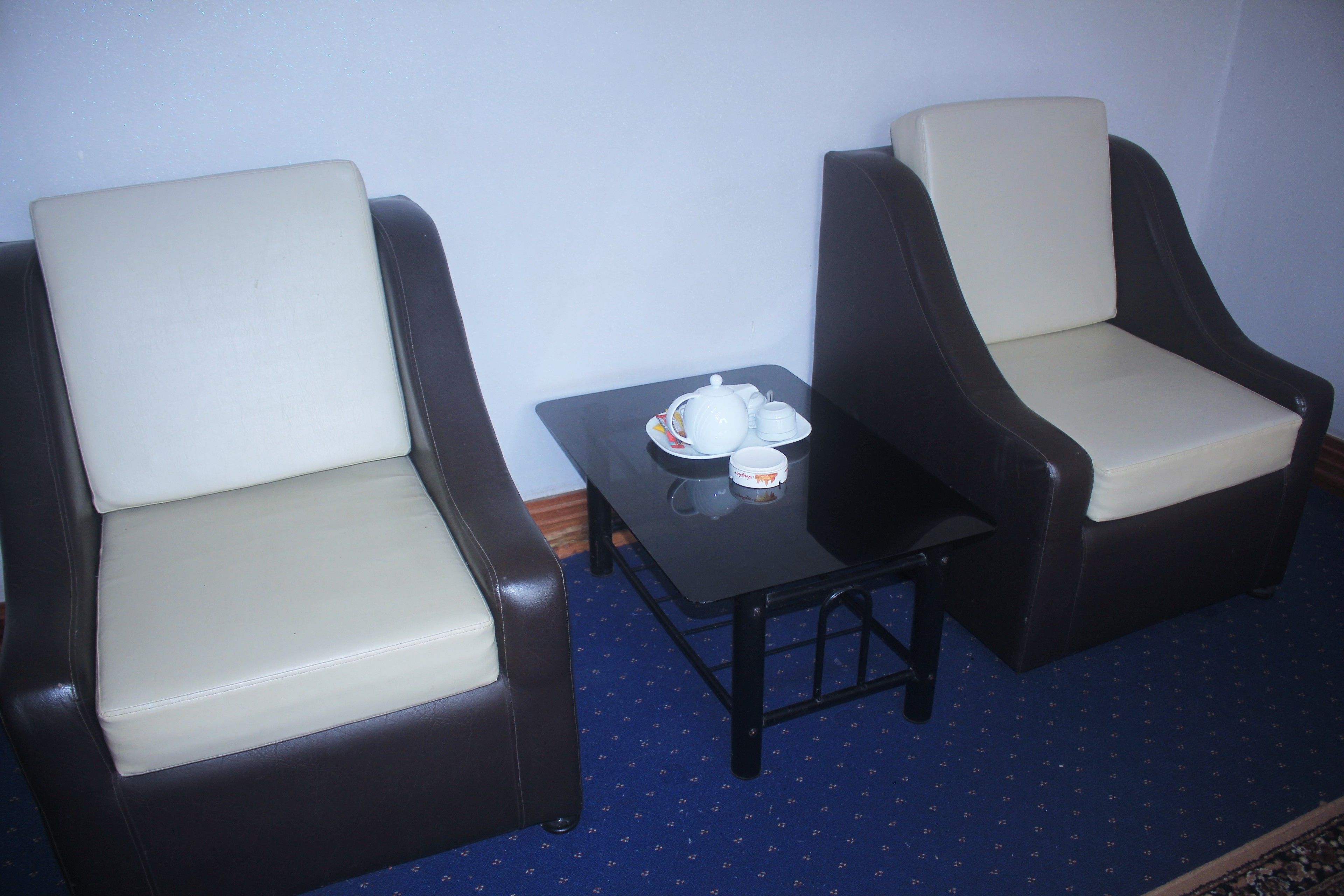 Dos sillones con una mesita entre ellos, una bandeja con tetera y tazas sobre la mesa.