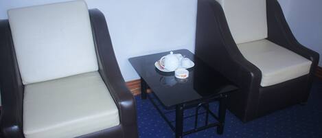 Deux fauteuils, une petite table placée entre eux, et sur la table, un plateau avec une théière et des tasses.