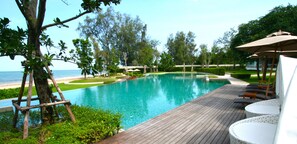 A swimming pool with a wooden deck, lounge chairs, and umbrellas.