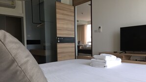 Hotellihuone, jossa on sänky, televisio, peili ja puinen vaatekaappi.