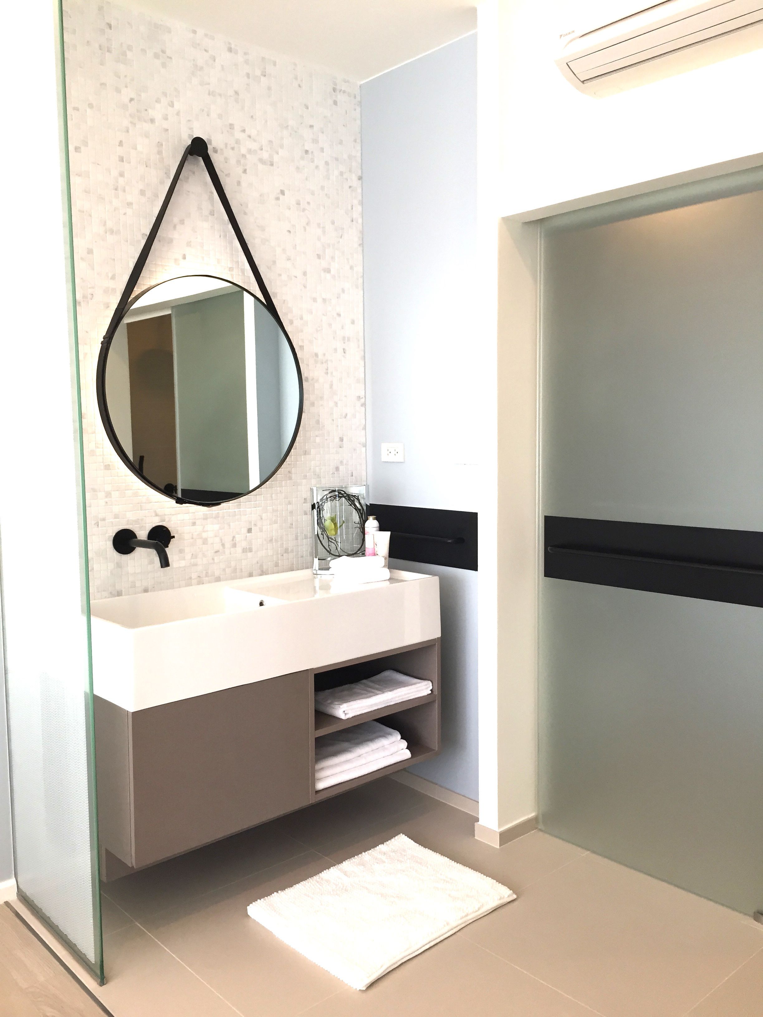 Une salle de bain moderne avec une douche à parois de verre, un meuble-lavabo blanc doté d’un robinet noir et un grand miroir.