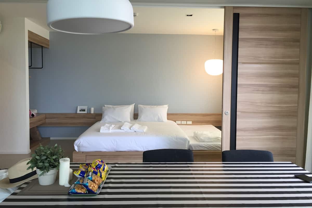A hotel room with a bed, bedside table, and a view of the outside.